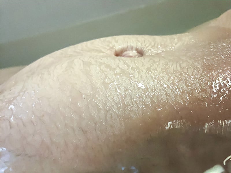 Close-up of a wet belly revealing pregnancy.